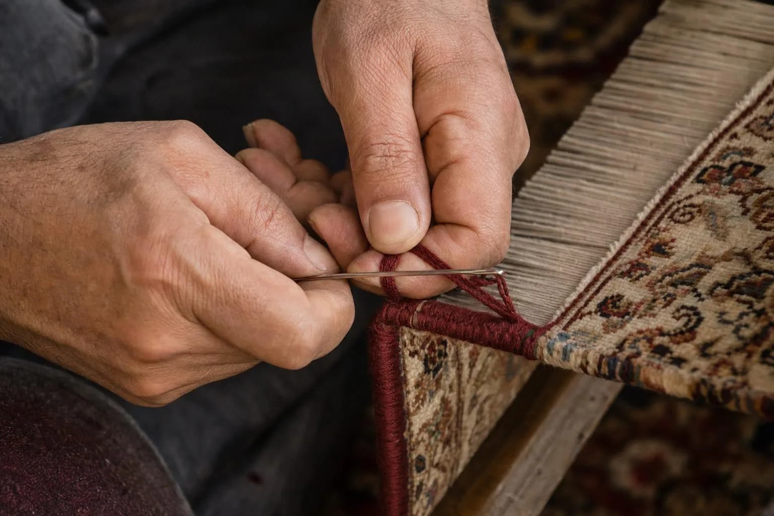 Teppichreparatur: Kante eines Perserteppichs wird in Schirasi-Technik neu mit Wolle umwickelt